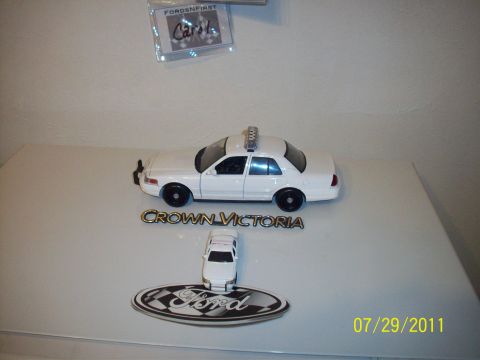 1998 Ford Crown Victoria - A white toy police car is displayed with a smaller Ford emblem and a Crown Victoria nameplate.