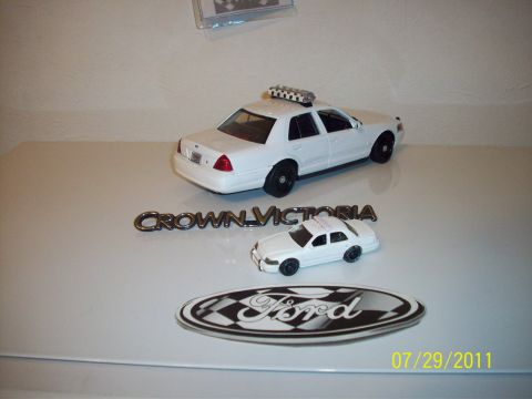 1998 Ford Crown Victoria - Model cars and emblems displayed together, including two Ford Crown Victoria models.