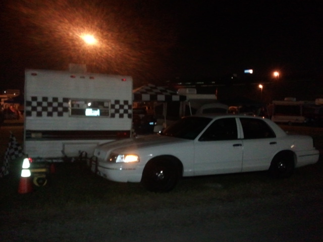 White 1998 Ford Crown Victoria sedan parked at night next to a trailer