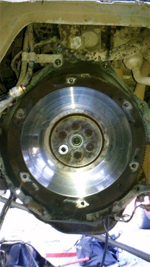 1995 Ford F-150 - A close-up view of a vehicle's flywheel and transmission bell housing, revealing mechanical components and mounting bolts.