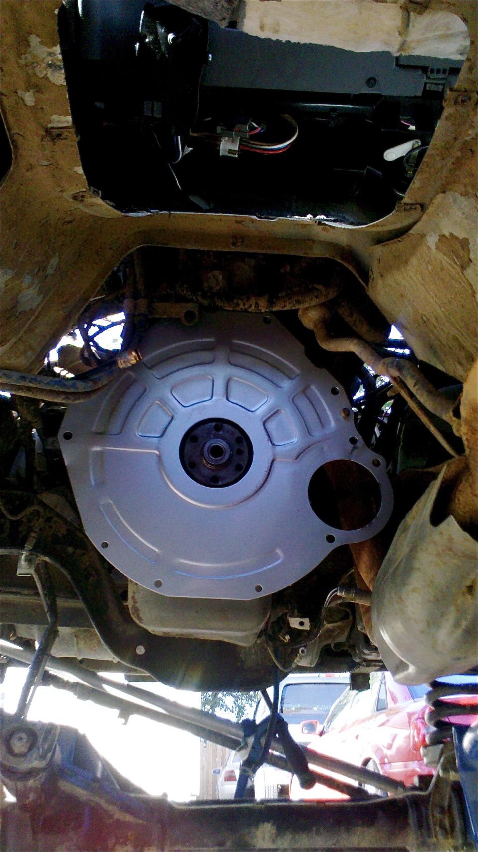 Underside view of a transmission bell housing with some wiring above it