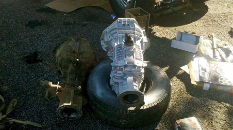 1995 Ford F-150 - Two transmissions and a tire are laid out on the ground, possibly for repair or sale.