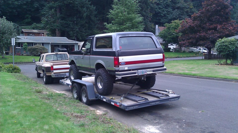 Silver and black Ford Bronco on a trailer, rear view. Red and white stripe on tailgate
