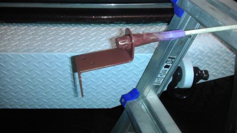 1989 Ford Bronco - A metal bracket is secured to a diamond plate surface, with a ladder positioned nearby.