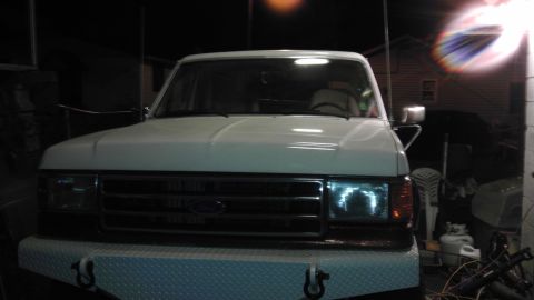 1989 Ford Bronco - The front of a white Ford Bronco is shown, a custom diamond plate bumper and a dark grille.