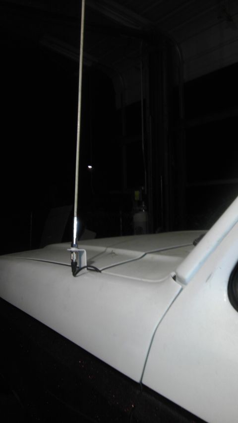 1989 Ford Bronco - Close-up of a car antenna mounted on the hood of a white vehicle.