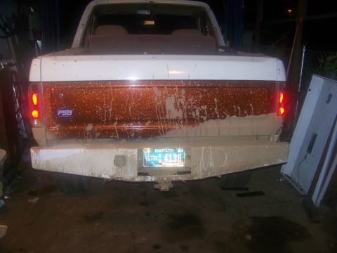 1989 Ford Bronco - The rear of a 1989 Ford Bronco, seen in a garage, is covered in mud with a distinctive glittery stripe.