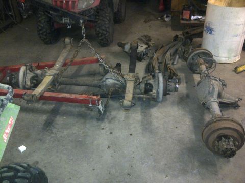 1979 Ford E250 - Vehicle axles and suspension components are suspended by an engine hoist in a garage setting.