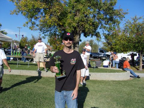 2007 Ford Mustang - A man holds a trophy at an outdoor event with other attendees and vehicles visible.