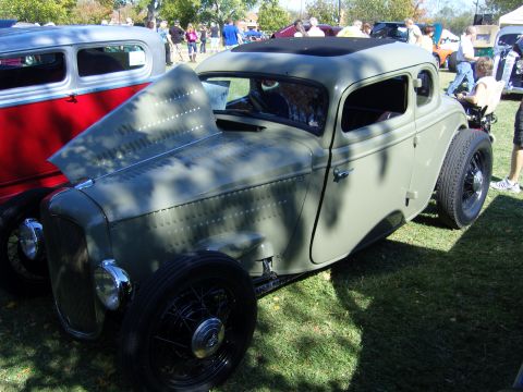 2007 Ford Mustang - A vintage hot rod coupe is displayed outdoors with its hood open, alongside another vehicle.