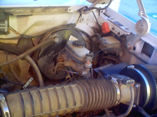 Engine bay showing air intake hose, brake fluid reservoir, and various hoses and wires