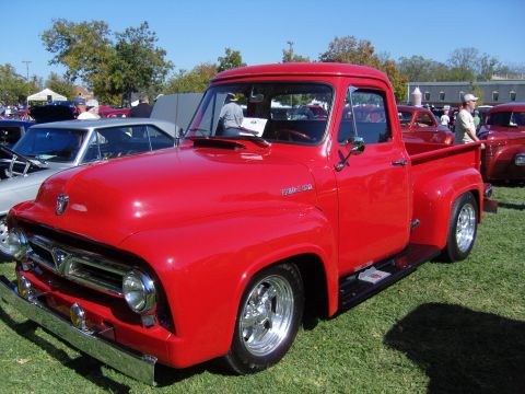 2007 Ford Mustang - A bright red 1953 Ford F-100 pickup truck is displayed at an outdoor event with other vehicles.
