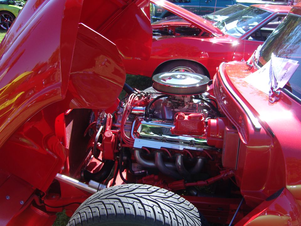 Red engine bay with chrome air cleaner and headers. Tire in foreground