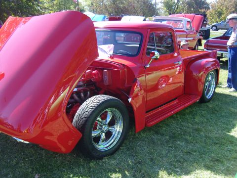 2007 Ford Mustang - Customized red 1956 Ford F-100 pickup truck on display at a car show.