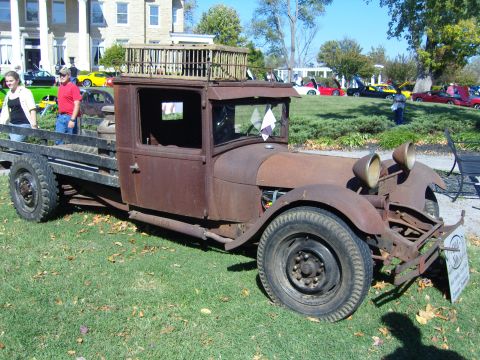 2007 Ford Mustang - Old flatbed truck with a wooden structure on its roof sits on display.