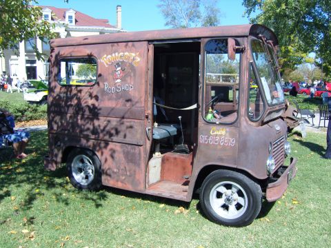 2007 Ford Mustang - A vintage delivery van, showing significant rust, is parked on a grassy lawn with a building in the background.