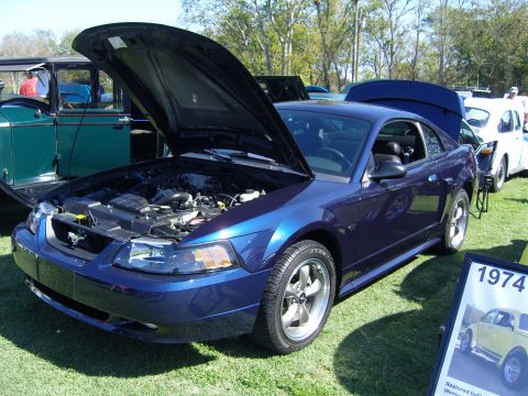 2007 Ford Mustang - A blue 2007 Ford Mustang is displayed with its hood open, alongside other vehicles at an outdoor event.