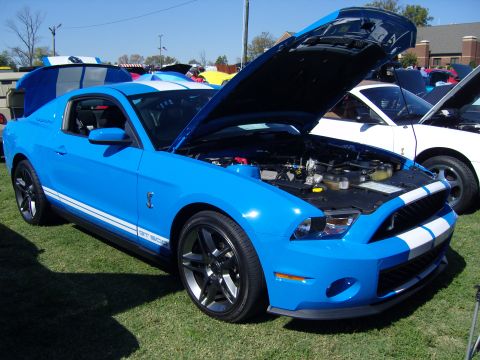 2007 Ford Mustang - A bright blue Ford Mustang GT500 with its hood open is displayed at an outdoor car show.