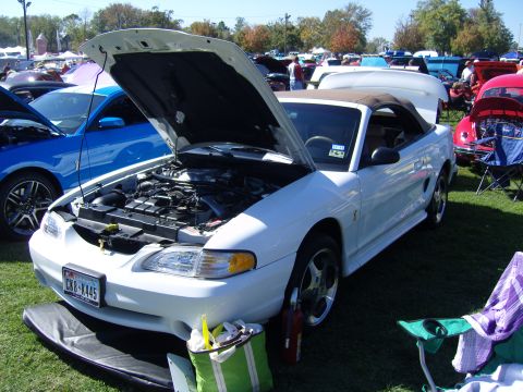2007 Ford Mustang - White convertible Mustang with hood open at an outdoor car show. Another car is visible to the left.