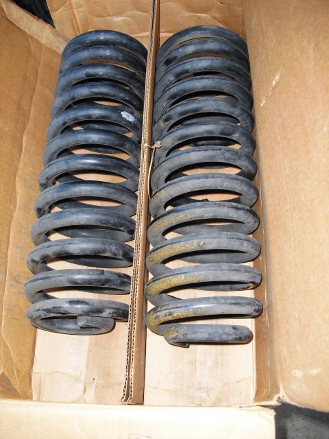 1986 Ford Bronco - Two sets of black coil springs are visible inside a cardboard box, with some rust on the right set.
