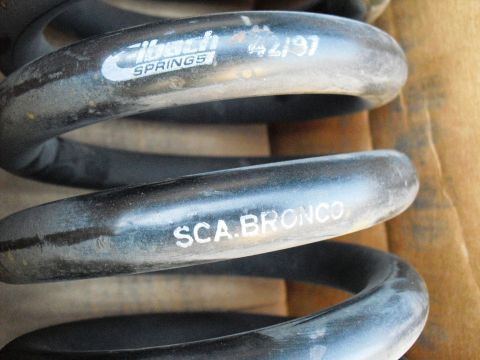 1986 Ford Bronco - A close-up of a black Eibach Springs coil spring, marked 'SCA.BRONCO' and a date code.