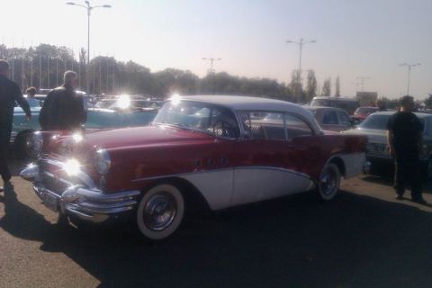 1991 Ford LTD Crown Victoria - A classic red and white coupe is displayed at an outdoor car show with other vehicles in the background.