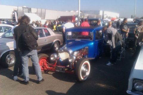 1991 Ford LTD Crown Victoria - A blue hot rod with exposed engine parts and red frame is displayed at an outdoor car show.