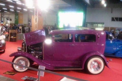 1991 Ford LTD Crown Victoria - A purple hot rod sedan is displayed indoors with its hood up, next to another vehicle.