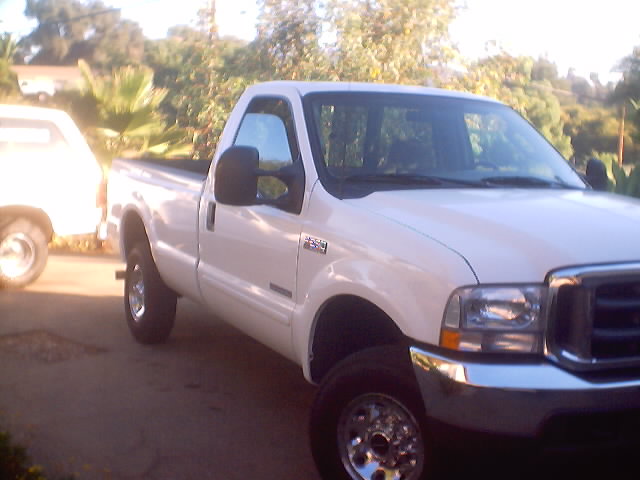 White Ford F-250 Super Duty regular-cab long-bed 4x4 with diesel badge parked on a driveway
