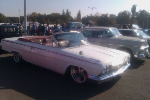 1991 Ford LTD Crown Victoria - A white convertible with a red interior and trim is parked at an outdoor event with other vehicles.
