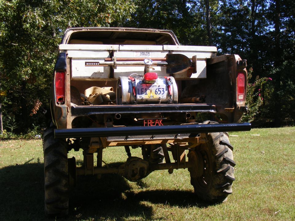 Rear view of a heavily modified pickup truck with large tires and equipment in the bed