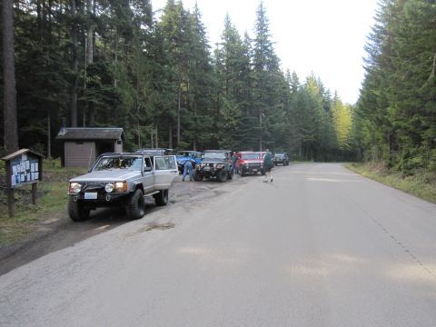 2008 Jeep Wrangler - Multiple off-road vehicles are parked on the side of a road in a wooded area.