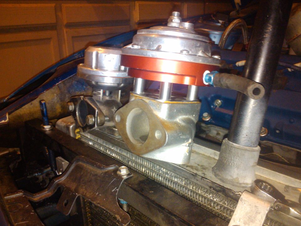 Turbocharger wastegate assembly with red and silver components mounted on a radiator