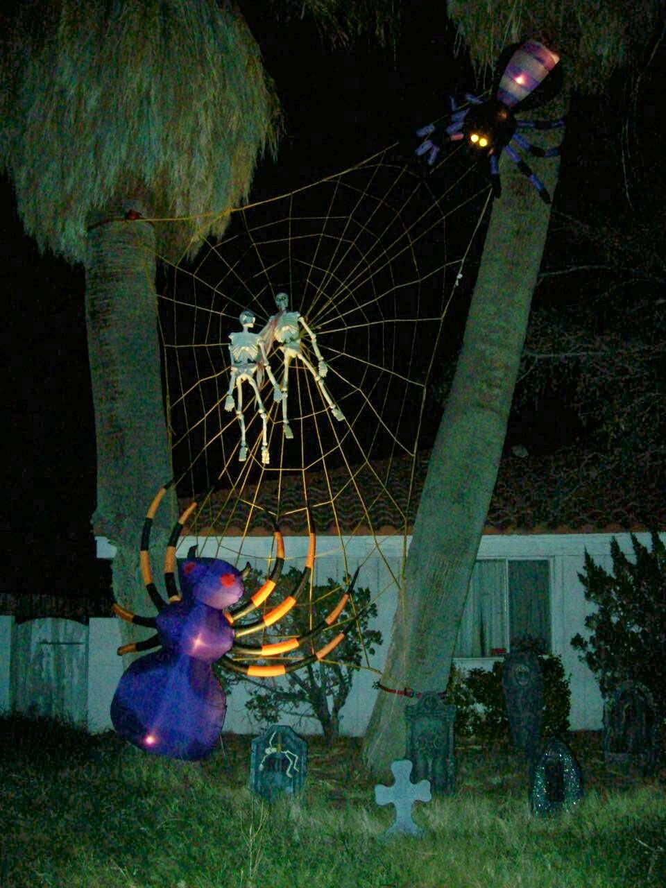 Inflatable spiders and skeletons on a web between palm trees for Halloween