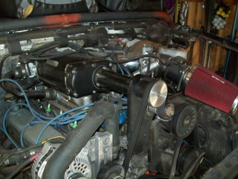 1993 Ford F-150 - Close-up view of a vehicle's engine bay, highlighting a black supercharger and a red air filter assembly.