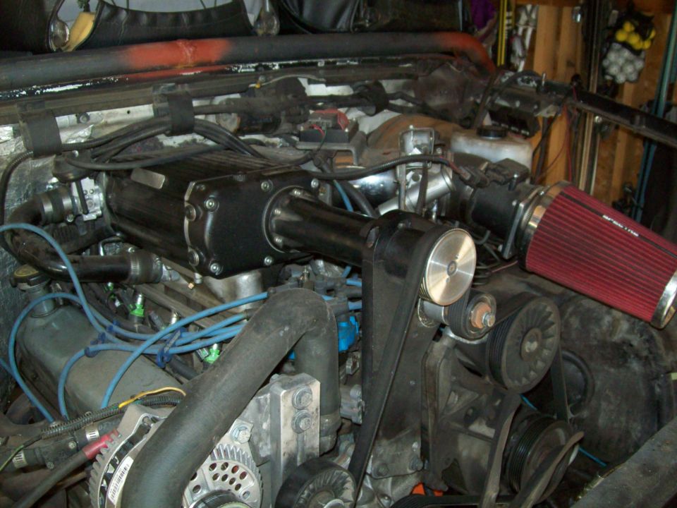 Supercharged V8 truck engine bay with blue plug wires and red cone air filter