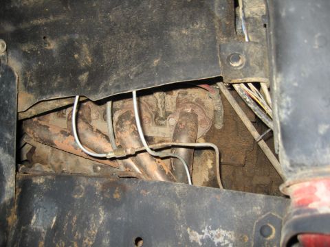 1979 Ford Bronco - Close-up view of exhaust manifold and associated brake lines, likely from an older vehicle.