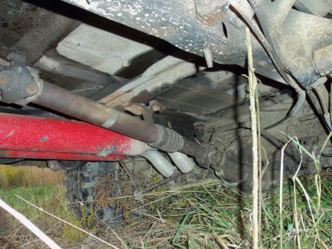 1985 Ford Bronco - The undercarriage of a vehicle shows the driveshaft, exhaust, and suspension components.