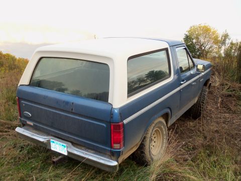1985 Ford Bronco - This blue and white Ford Bronco, seen from the rear 3/4 angle, appears to be from the early 1980s, not 1985.