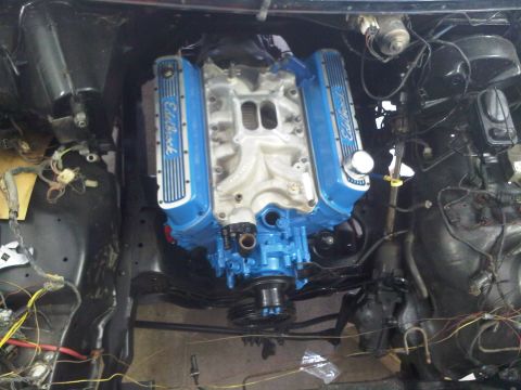 1985 Ford Bronco - The engine bay shows a V8 engine with blue valve covers and intake manifold, surrounded by wiring and other engine components.