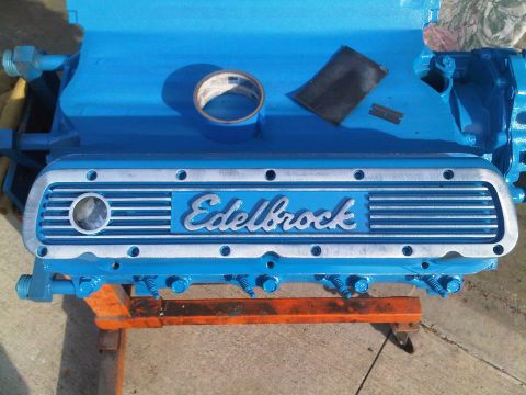 1985 Ford Bronco - Close-up of a blue engine block with an Edelbrock valve cover, resting on an orange stand.