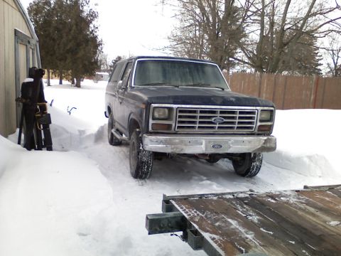 1985 Ford Bronco - Ford Bronco parked in snow next to a building, with a trailer in front.