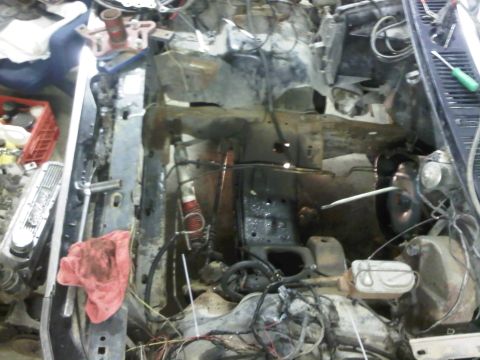 1985 Ford Bronco - The engine bay of a vehicle is shown disassembled, with many parts removed and wires exposed.