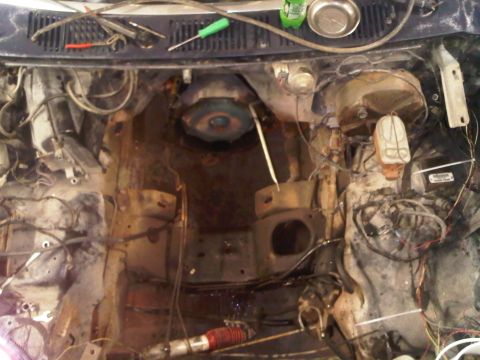 1985 Ford Bronco - The engine bay is mostly empty, with tools and a bottle of fluid on the cowl.