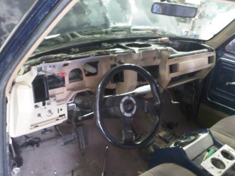 1985 Ford Bronco - The interior of a vehicle shows a disassembled dashboard and steering wheel, with visible wiring and components removed.