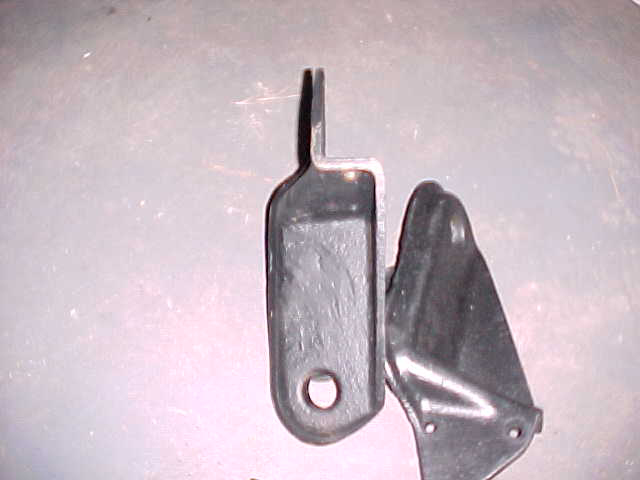 two black metal brackets, one with a hole, on a gray surface