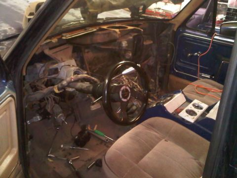 1985 Ford Bronco - The interior of a vehicle is shown with its dashboard and wiring exposed, indicating ongoing work or repair.