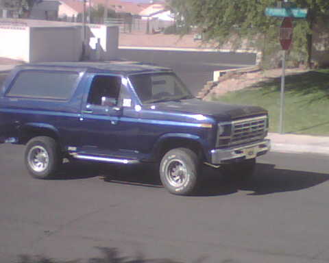 1985 Ford Bronco - A blue Ford Bronco is parked on the side of a residential street.