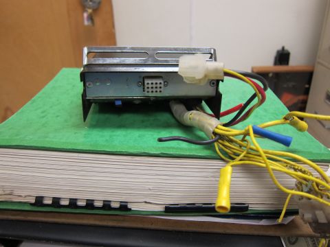 2001 Ford Crown Victoria - An electronic control module with multiple wires and connectors is shown from the side, placed on a large book.