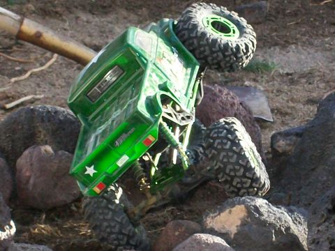 1985 Ford Bronco - A green remote control rock crawler truck is overturned on a rocky terrain.